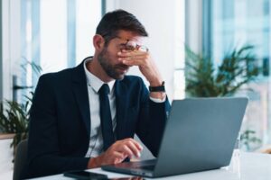 Frustrated, businessman or headache with laptop for stress, mistake or corporate bankruptcy at office