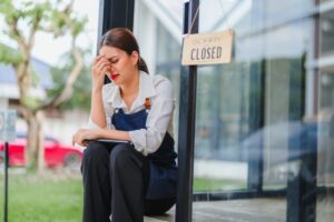 Small business owner worried about her closed cafe, sitting outside with a tablet
